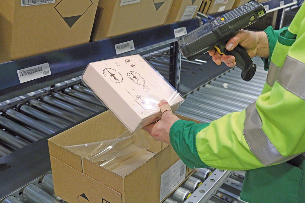 Magazijnmedewerker zet een artikel klaar met behulp van een Rf scanner die verbonden is aan de orderpicking software Magazijnmedewerker zet een artikel klaar met behulp van een Rf scanner die verbonden is aan de orderpicking software