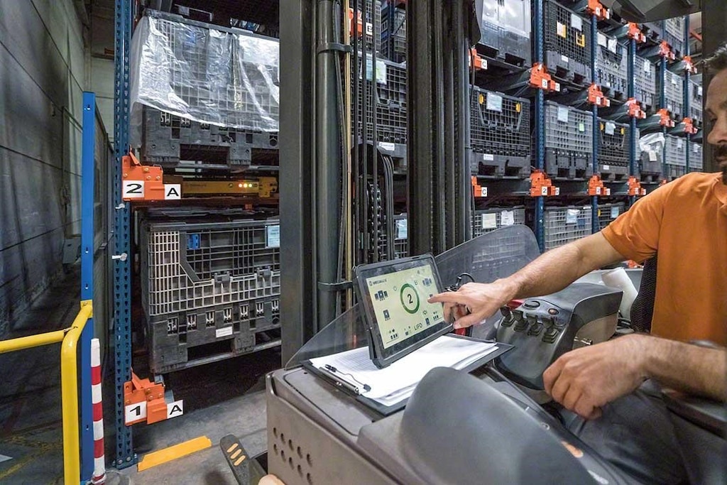 Vanaf de heftruck stuurt een magazijnmedewerker de Pallet Shuttle aan met behulp van een tablet Vanaf de heftruck stuurt een magazijnmedewerker de Pallet Shuttle aan met behulp van een tablet