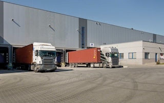 Vrachtwagens lossen de goederen bij de laad- en losperrons van een distributiecentrum