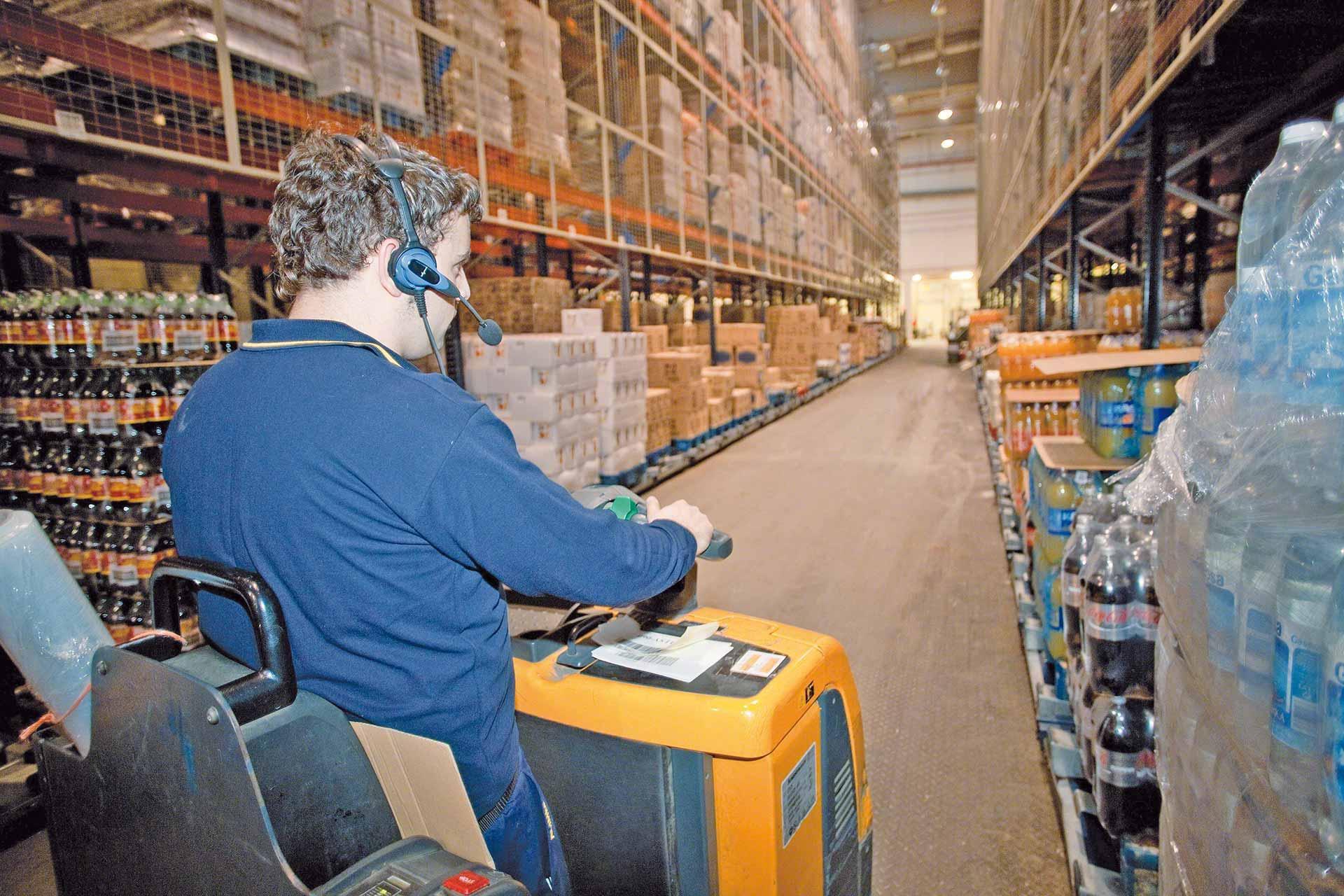 Een magazijnmedewerker zet bestellingen in dozen klaar, daarbij ondersteund door een voicepicking systeem