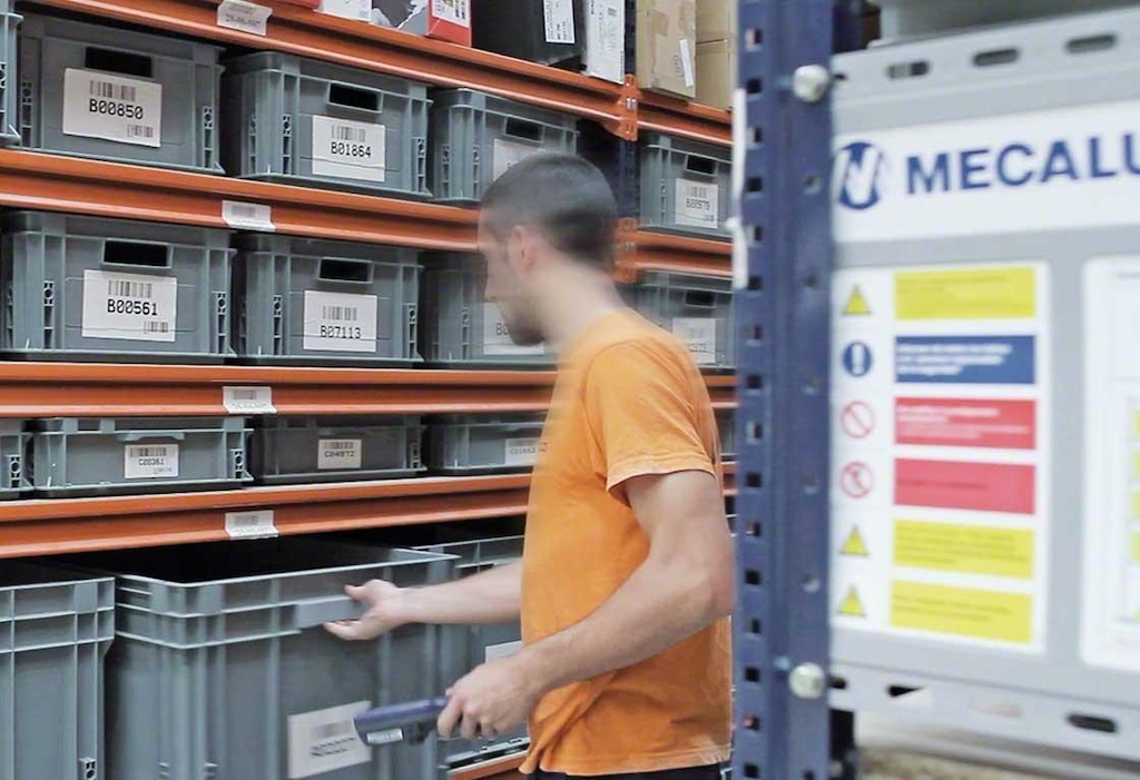 Een magazijnmedewerker haalt de artikelen uit de magazijnbakken Een magazijnmedewerker haalt de artikelen uit de magazijnbakken