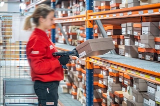 Een magazijnmedewerker verzamelt artikelen met de pick to cart-methode Een magazijnmedewerker verzamelt artikelen met de pick to cart-methode